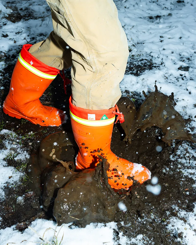 Man stepping into a puddle of mud wearing Kamik Workhorse field and work boots