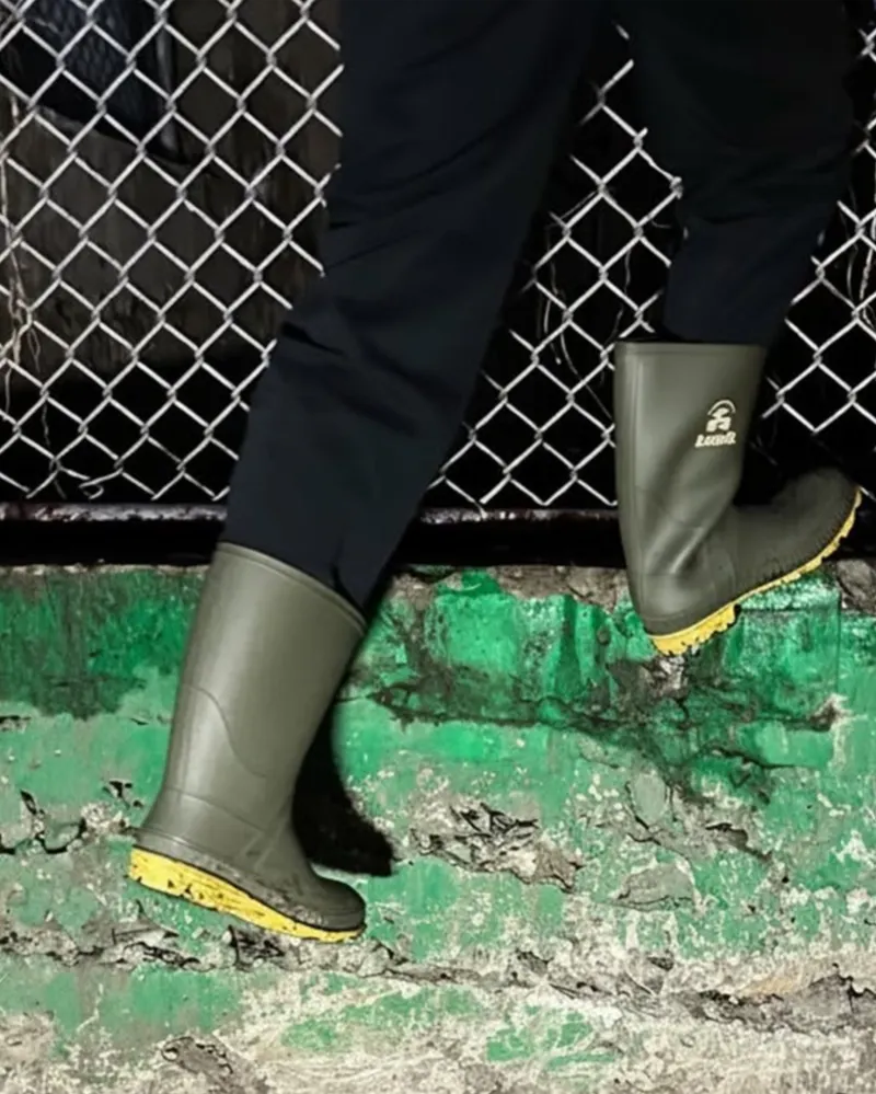 Kid climbing a fence wearing Kamik Stomp rain boots